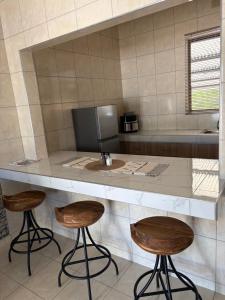 a kitchen with two stools and a counter with a sink at Pooltjie's Self-catering Overnight in Keetmanshoop
