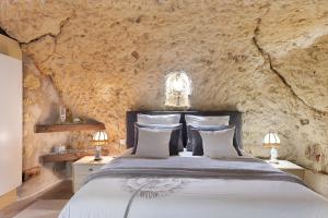 a bedroom with a large bed in a stone wall at Les Iris - Maison Troglodytique in Trôo