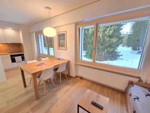 a dining room with a table and a large window at Belmont Seegarten in Lenzerheide