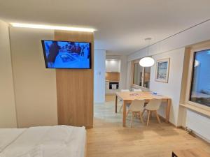 a dining room with a table and a television on a wall at Belmont Seegarten in Lenzerheide