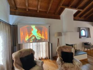 a living room with two chairs and a large tv at Ferienwohnung Selina in Lenzerheide