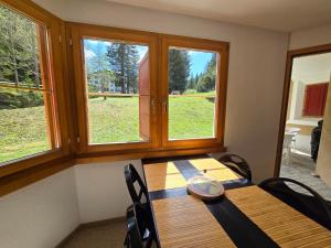 a dining room with a table and two windows at Ferienwohnung Selva in Lenzerheide