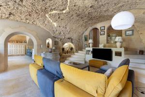 a living room with a couch and a tv at Les Iris - Maison Troglodytique in Trôo