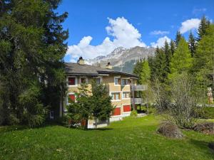 a building in the middle of a field with trees at Ferienwohnung Selva in Lenzerheide