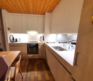 a kitchen with white cabinets and a sink and a table at Triangel C Kiefer in Parpan