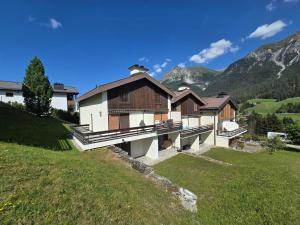 a house on a hill with mountains in the background at La Schmetta 65 Quadroni in Lenzerheide