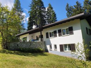 a white house with black windows and a stone wall at Ferienhaus Tina in Lenzerheide