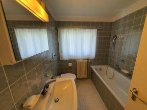 a bathroom with a tub and a toilet and a sink at Ferienhaus Tina in Lenzerheide +23 photos