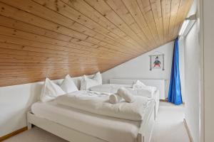 two beds in a room with a wooden ceiling at Triangel B Rezia in Parpan