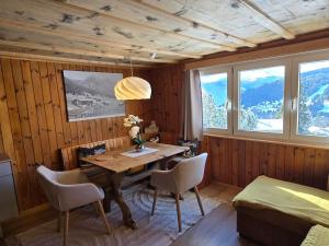 a dining room with a table and chairs and windows at Maiensäss Crapera in Lenzerheide