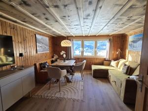 a living room with a table and a couch and a television at Maiensäss Crapera in Lenzerheide