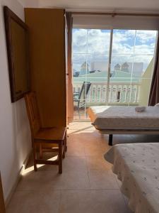 a room with a bed and a chair and a window at VV Monica 33 "by AFCVacacional" in Puerto Naos