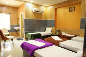a room with three beds and a chair in it at SSR Hotel in Srikalahasti