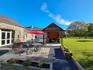 a patio with a table and chairs and a red umbrella at Dryslwyn Cottage in Carmarthen