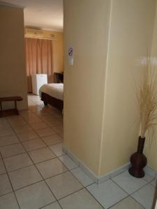 um quarto com uma cama e um vaso num piso de azulejo em Hardrock Guest House em Francistown