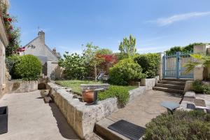 a garden with stone walls and a yard with stairs at Les Iris - Maison Troglodytique in Trôo