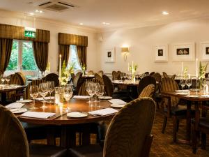 a dining room with tables and chairs with wine glasses at Macdonald Frimley Hall Hotel & Spa in Camberley