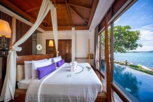 a bedroom with a bed and a view of the water at The Sarann Koh Samui, Suites & Villas in Chaweng Noi Beach