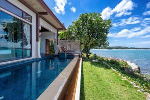 a house with a swimming pool next to the water at The Sarann Koh Samui, Suites & Villas in Chaweng Noi Beach