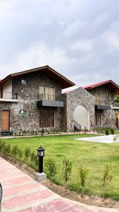 a large stone building with a green lawn in front at Hill Turn Corbett in Rāmnagar