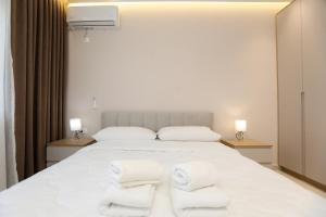 a bedroom with a white bed with towels on it at Alrei Apartment in Vlorë