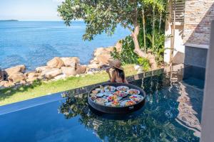 a woman sitting on a pool with a tray of food at The Sarann Koh Samui, Suites & Villas in Chaweng Noi Beach