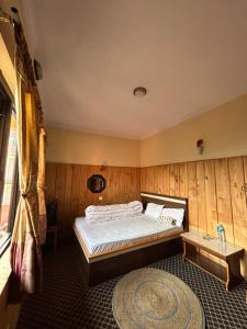 a bedroom with a bed in a room with wooden walls at Berg House Cafe and Hotel in Nagarkot