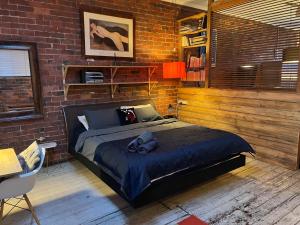 a bedroom with a bed and a brick wall at beachside loft warehouse artists retreat in Edithvale