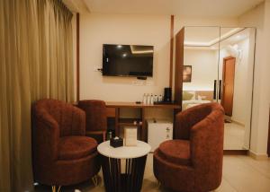 a room with two chairs and a table and a television at Hotel Calicut Beach-Silk Street in Kozhikode
