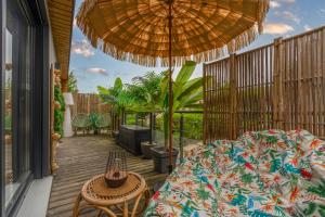 a patio with a table and an umbrella at Lodge de la Jungle avec Spa in Nanteuil-lès-Meaux