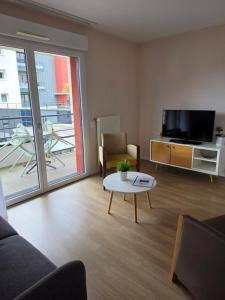 a living room with a couch and a tv and a table at Domitys Le Griffon d’Or in Saint-Brieuc