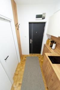 a small kitchen with a black door and a kitchen rug at Apartman Gorica in Priboj +12 photos