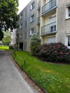 an apartment building with a lawn and flowers in front of it at Escale Rennes in Rennes