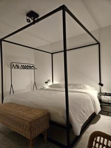 a bedroom with a black canopy bed with a wicker bench at La Cereria INES in Chiavenna