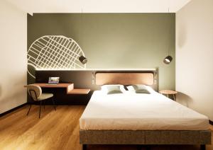 a bedroom with a bed and a desk and a chair at Essential by Dorint Mannheim Taylor Park in Mannheim