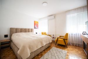 a bedroom with a large bed and two chairs at Apartman Gorica in Priboj