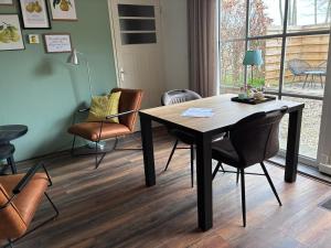 a dining room with a wooden table and chairs at Appels en Peren Bed and Breakfast in Breezand