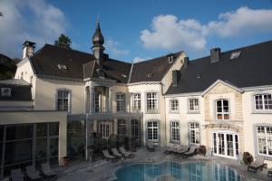 een groot wit gebouw met een zwembad ervoor bij Le Chateau Des Thermes in Chaudfontaine