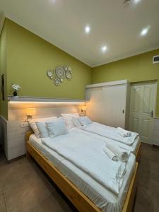 a bedroom with a large bed with white sheets at Szem-s Üdülő és Lakópark a Szem-s Vendégház új neve in Balatonszemes