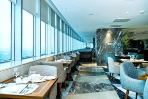 a restaurant with tables and chairs and windows at The Premier Centauras in Islamabad
