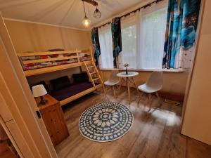 a bedroom with a bunk bed and a table and chairs at POD SOSNAMI - ul Dominicka 28 in Boszkowo