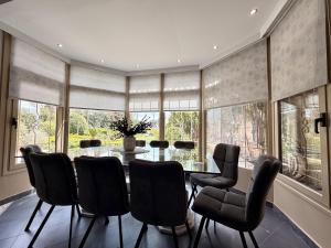 a dining room with a table and chairs and windows at Natalie Apartments Athens Airport in Artemida