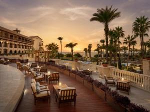 a hotel patio with tables and chairs and palm trees at Elysium in Paphos
