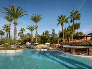 a swimming pool at a resort with palm trees at Elysium in Paphos