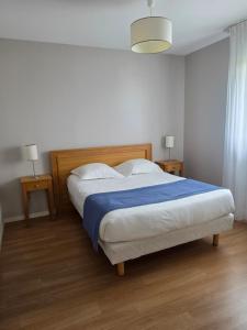 a bedroom with a large bed with a blue blanket at Domitys Le Griffon d’Or in Saint-Brieuc