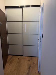 a closet with white doors and a wooden floor at Apartament Londyn in Pniewy +4 photos