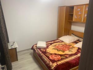 a small bedroom with a bed with a floral blanket at Sofia Apartament in Drobeta-Turnu Severin
