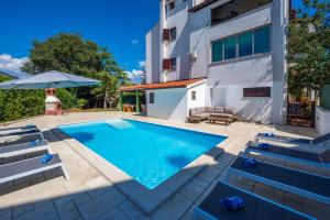 a swimming pool with chairs and an umbrella next to a building at Moonvidal residence with big private swimming pool and free parking in Pula