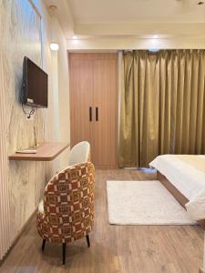 a hotel room with a bed and a chair and a tv at The Kaksh in Greater Noida