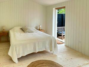 a white bedroom with a bed and a sliding glass door at Charming Beach Cottage In Gilleleje in Gilleleje